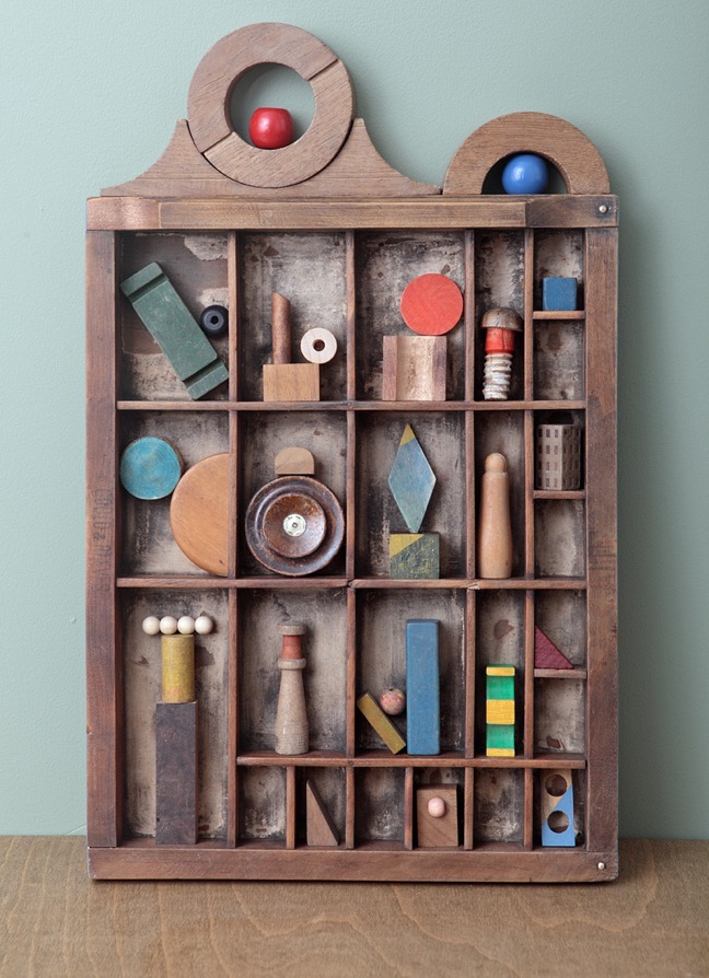 Assemblage artwork of old wooden blocks in an Antique letterpress printers type case drawer tray 