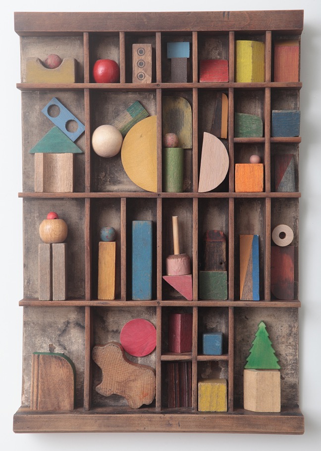 Assemblage artwork of old wooden blocks in an Antique letterpress printers type case drawer tray 