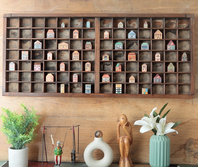 Quirky little wooden houses and buildings displayed in an old letterpress printers tray