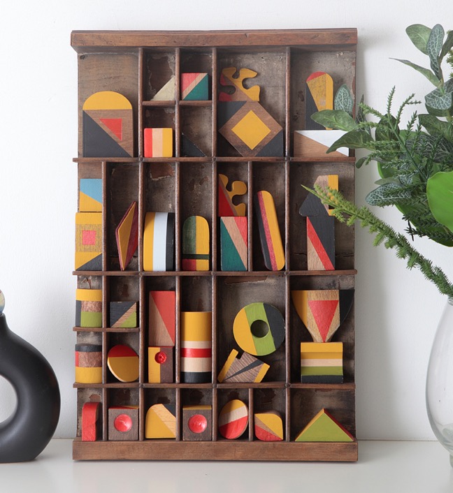 Assemblage artwork of old wooden blocks in an vintage letterpress printers type case drawer tray 