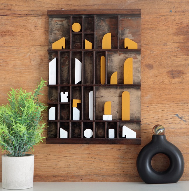 Assemblage artwork of old wooden blocks in an vintage letterpress printers type case drawer tray 